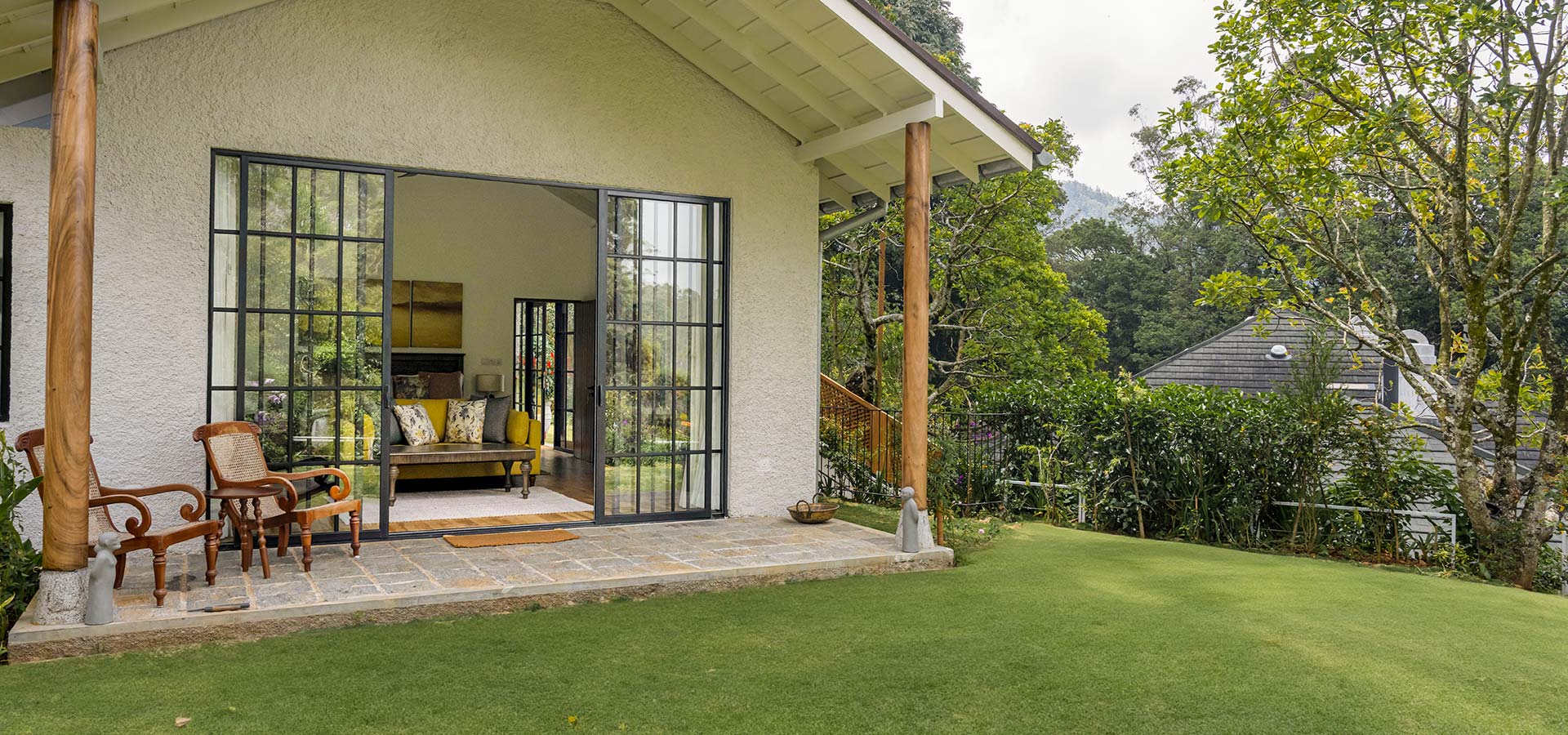 A cottage suite with glass doors open onto a veranda and the lawn